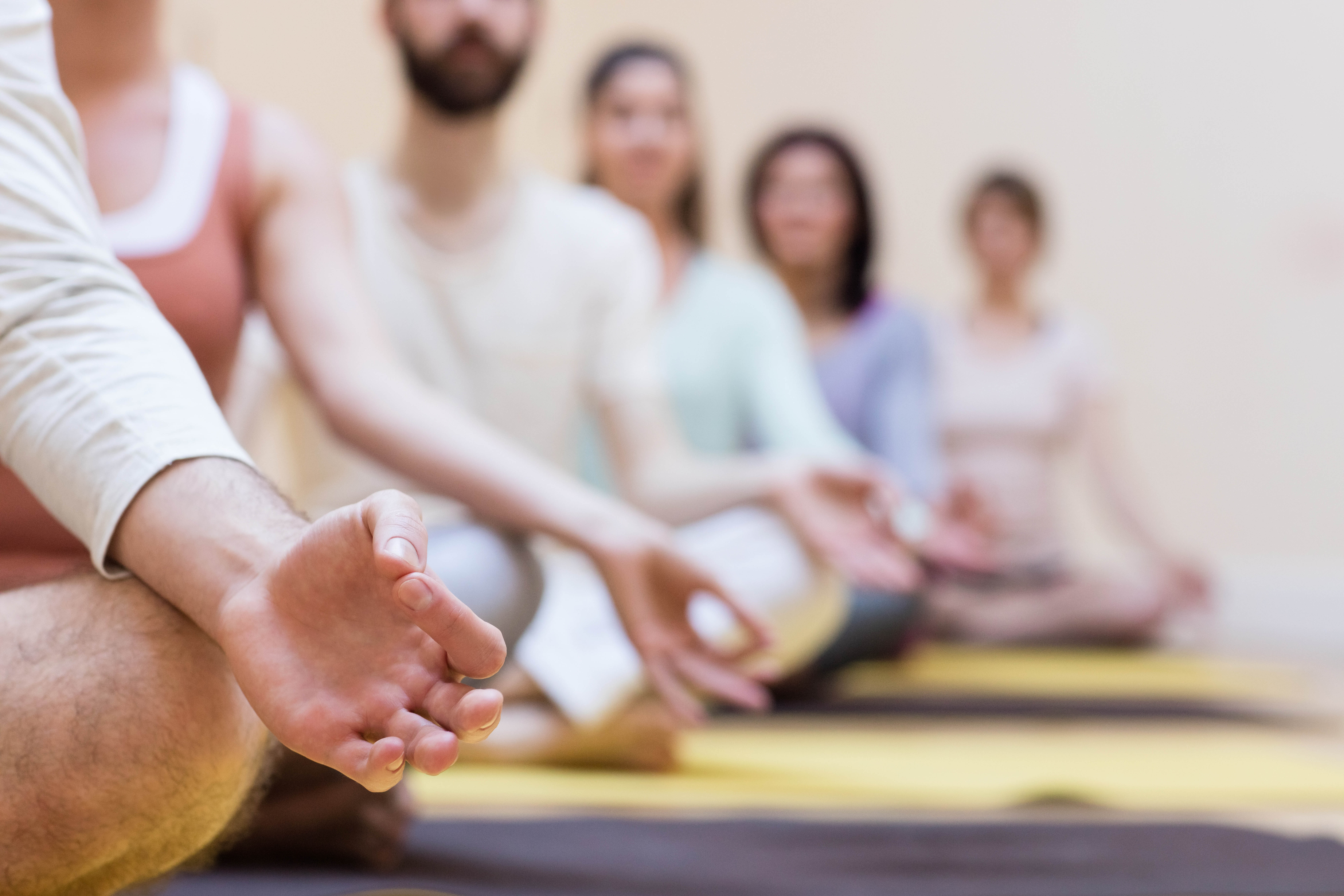 Group of people doing meditation on exercise mat in the fitness studio